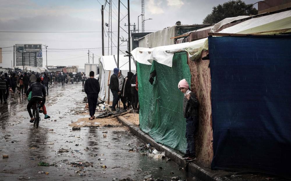 Palestinian people walk and ride past tents at a makeshift camp housing displaced Palestinians, in Rafah in the southern Gaza Strip on Tuesday. AFP