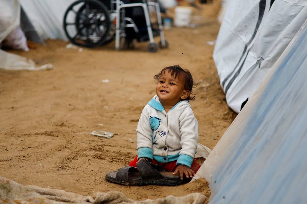 A displaced Palestinian child, who fled their home due to Israeli strikes, shelters at a tent camp in Rafah, southern Gaza Strip on Tuesday. REUTERS