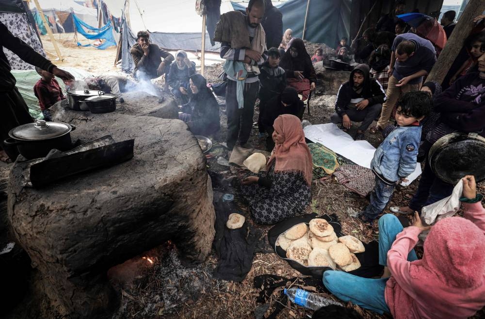 Palestinian women make break in ovens at a makeshift camp housing displaced Palestinians, in Rafah in the southern Gaza Strip on Tuesday. AFP