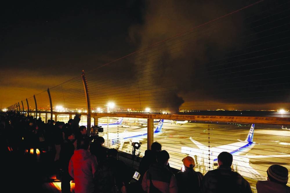 
Passengers watch from observation deck as a Japan Airlines’ A350 airplane burns at Haneda International Airport in Tokyo. 