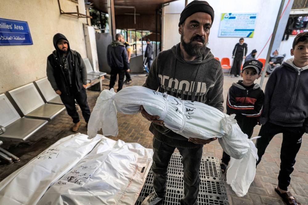A relative carries one of the bodies of the Jabalieh family who were killed when the building where they were sheltering was hit by Israeli bombardment, at the morgue of al-Najjar hospital in Rafah in the southern Gaza Strip, on Wednesday. AFP