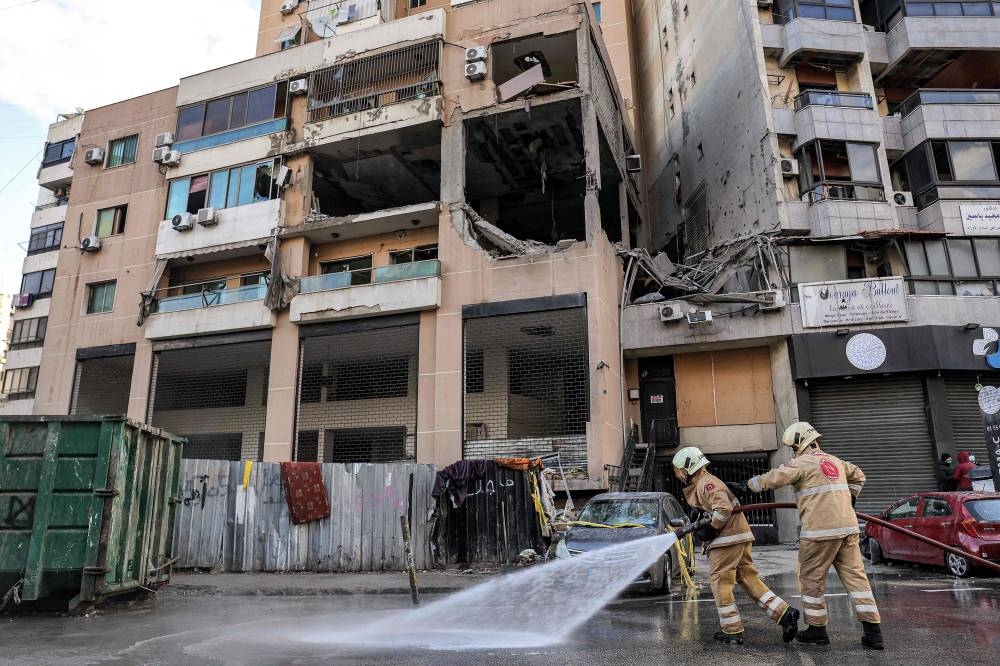 Lebanese civil defence members spray with water the street by the building that was hit by an Israeli strike targeting Hamas deputy leader Saleh al-Aruri in the southern suburb of Beirut on Wednesday. AFP