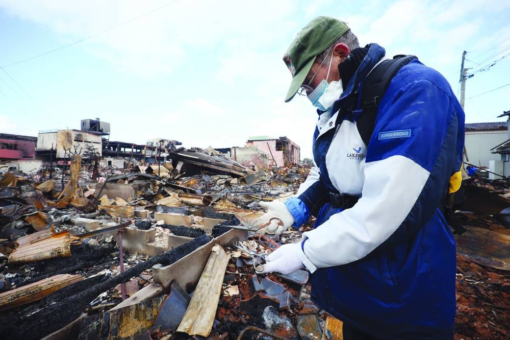 
A man finds his wife’s sewing scissors at their home which was destroyed by fire in the city of Wajima. 