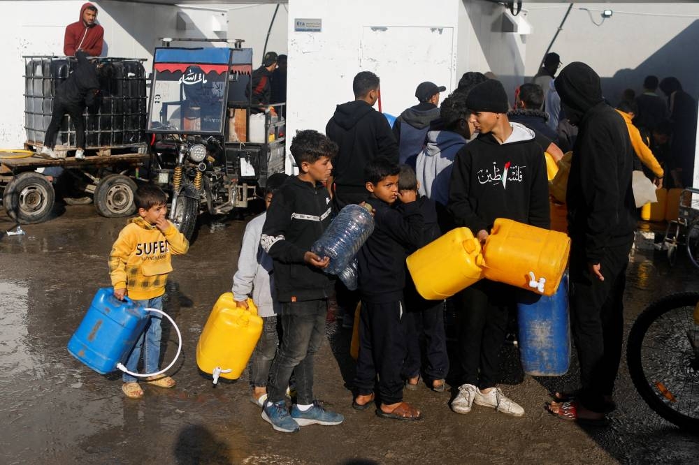 Palestinian children queue as they wait to collect drinking water, amid shortages of drinking water in Rafah, in the southern Gaza Strip, on Friday. REUTERS