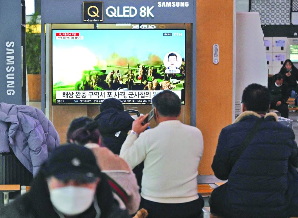 
People watch a television screen showing a news broadcast with file footage of North Korea’s artillery firing, at a railway station in Seoul. 