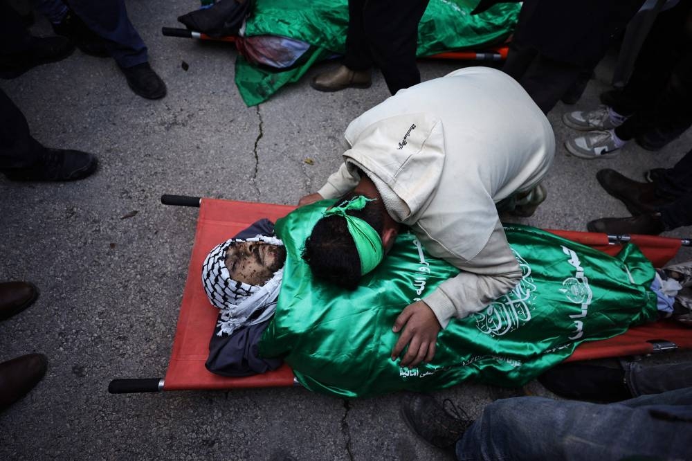 A man mourns over the flag-draped bodiy of one of six Palestinians killed during an Israeli raid in Jenin in the occupied West Bank, during their funeral on Sunday. AFP