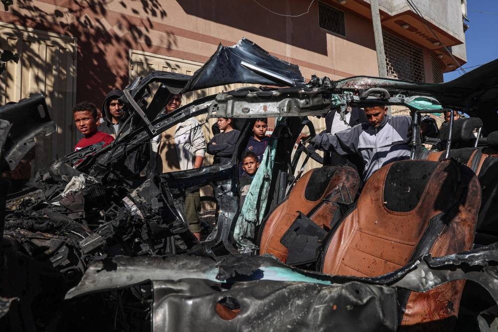 People check the car in which two journalists, Mustafa Thuria, a video stringer for AFP news agency, and Hamza Wael Dahdouh, a journalist with Al Jazeera television network, were killed in a reported Israeli strike in Rafah in the Gaza Strip on Sunday. AFP.