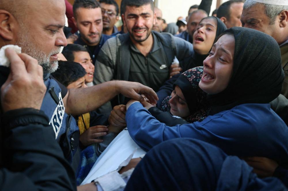 The widow (R) of Hamza Wael Dahdouh, a journalist with the Al Jazeera television network, and his father Al Jazeera's bureau chief in Gaza, Wael Al-Dahdouh (L) mourn over his body during his funeral, after he was killed in a reported Israeli air strike, in Rafah in the Gaza Strip on Sunday. AFP