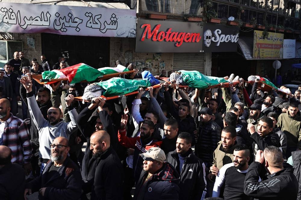 Mourners carry the flag-draped bodies of Palestinians killed during an Israeli raid in Jenin in the occupied West Bank, during their funeral on Sunday. AFP