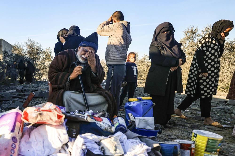 A displaced Palestinian man reacts as he sits among objects salvaged from a house that was used as a shelter by his extended family members, many of whom were reported killed when it was destroyed during an Israeli strike on Rafah in the southern Gaza Strip on Sunday. AFP