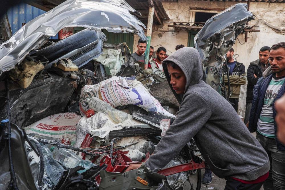 A Palestinian youth inspects a car wreck following reported Israeli bombardment in Rafah in the southern Gaza Strip on Monday. AFP