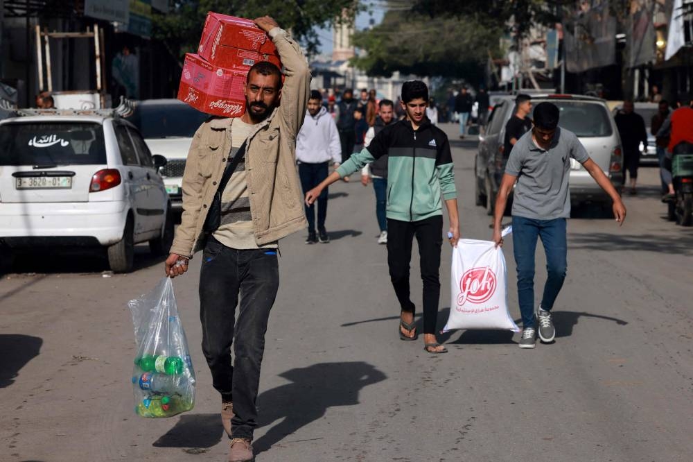 Palestinian men carry their shopping at a market in Rafah refugee camp in the Gaza Strip on Monday. AFP