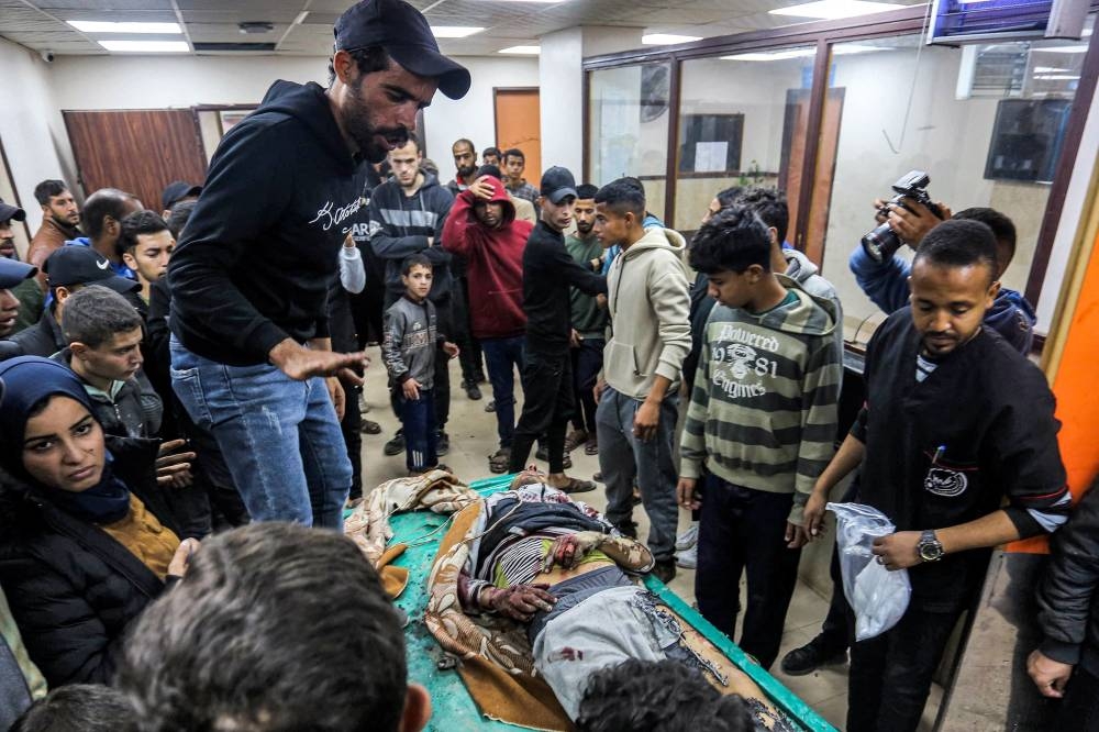 People gather around the body of a youth who was killed in Israeli bombardment as it is brought into Shuhada al-Aqsa (Aqsa Martyrs) Hospital in Deit al-Balah in the central Gaza Strip on Monday. AFP 
