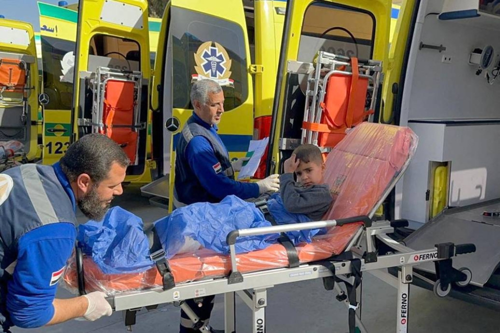 Egyptian paramedics transport an injured Palestinian child to a Red Crescent ambulance upon his arrival from Gaza via the Rafah border crossing, on Wednesday. AFP