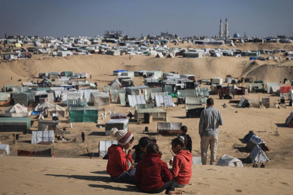 Displaced Palestinian children play on a sand dune overlooking a makeshift camp on the Egyptian border, west of Rafah in the southern Gaza Strip on Sunday. AFP