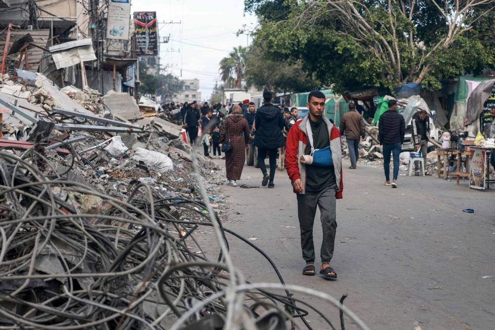 People walk amid destroyed buildings in Rafah on the southern Gaza Strip on Sunday. AFP