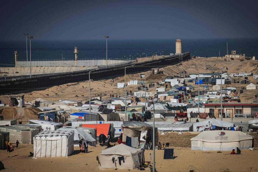 Displaced Palestinians gather at a makeshift camp on the Egyptian border, west of Rafah in the southern Gaza Strip on Sunday. AFP