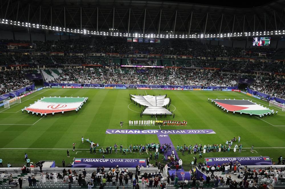 General view as a banner of the AFC Asian Cup, the Iran and Palestine flags are seen as the players line up during the national anthems before the match. REUTERS