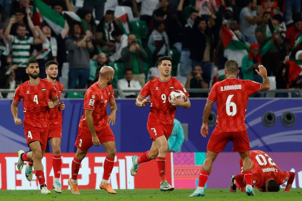Palestine's midfielder Tamer Seyam celebrates with his teammates after scoring their first goal during the Qatar 2023 AFC Asian Cup Group C football match between Iran and Palestine at the Education City Stadium. AFP