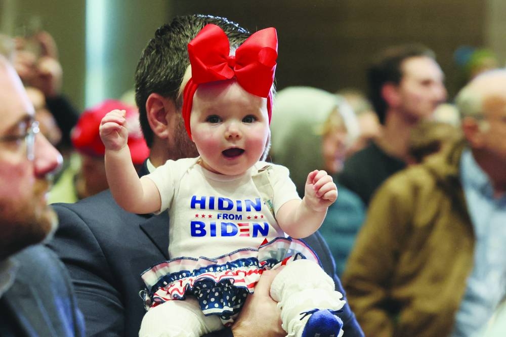 A Trump supporter holds a baby during the campaign event of former US president and Republican 
presidential candidate Donald Trump, in Indianola, Iowa, yesterday. (Reuters)
