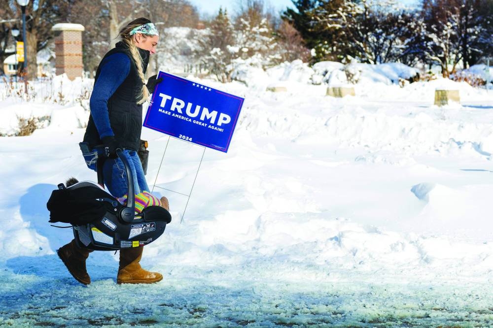 A supporter carries her baby and a Trump placard as she braves the below zero temperatures to attend the rally in Indianola. (AFP)