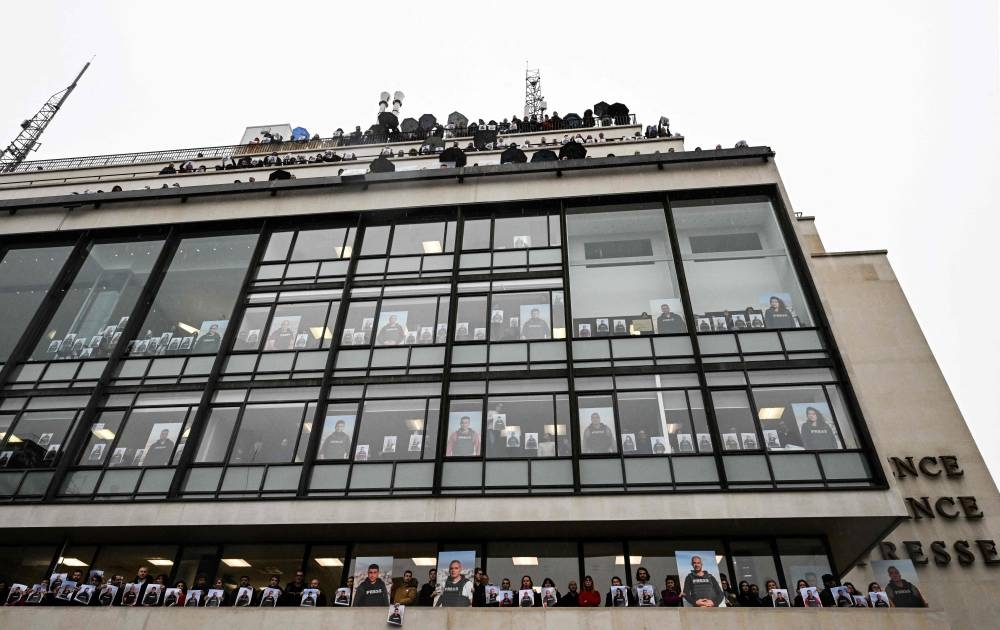 Agence France Presse employees pose on the balconies and in front of windows of the agency's headquarters in Paris, Wednesday, holding portraits in support of AFP journalists working in Gaza. 