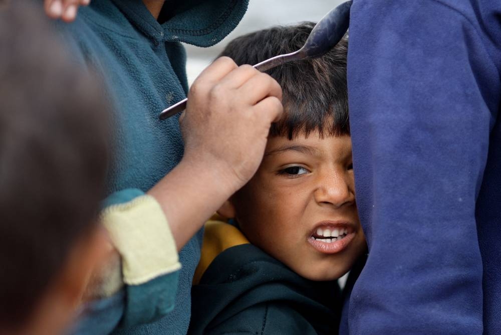 A boy reacts as Palestinians wait to receive food amid shortages of food supplies in Rafah in the southern Gaza Strip on Wednesday. REUTERS