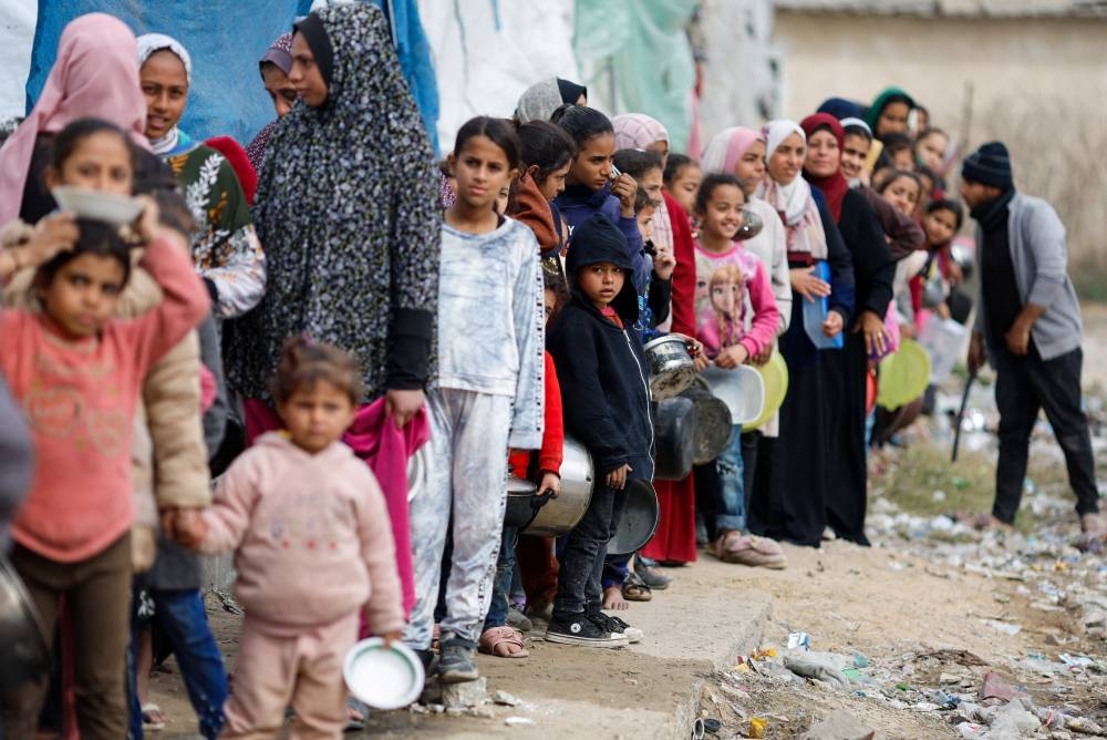 Palestinians stand in a line as they wait to receive food amid shortages of food supplies, in Rafah in the southern Gaza Strip on Wednesday. REUTERS
