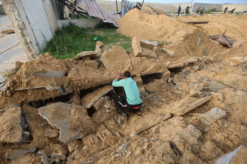 A Palestinian man checks damaged graves at a cemetery following an Israeli raid in Khan Younis in the southern Gaza Strip on Wednesday. REUTERS