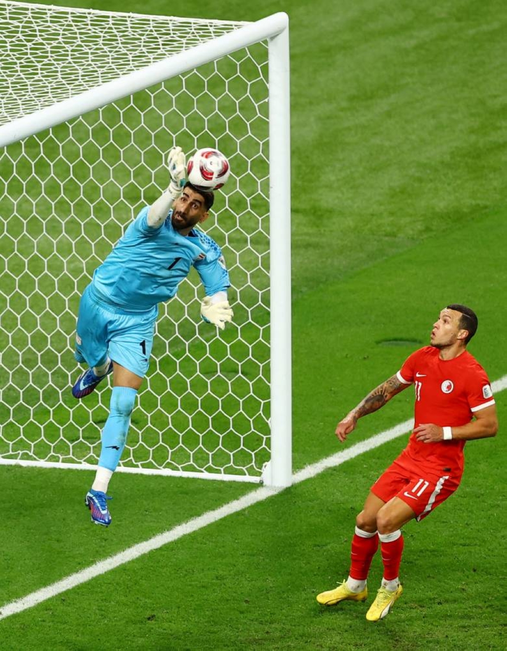 Iran's Alireza Beiranvand in action with Hong Kong's Everton Camargo. REUTERS