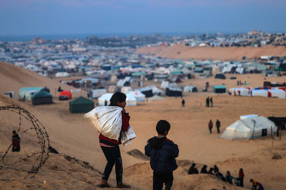 Displaced Palestinian children walk on a hill facing their makeshift camp in Rafah, on the southern Gaza Strip on the border with Egypt on Friday. AFP