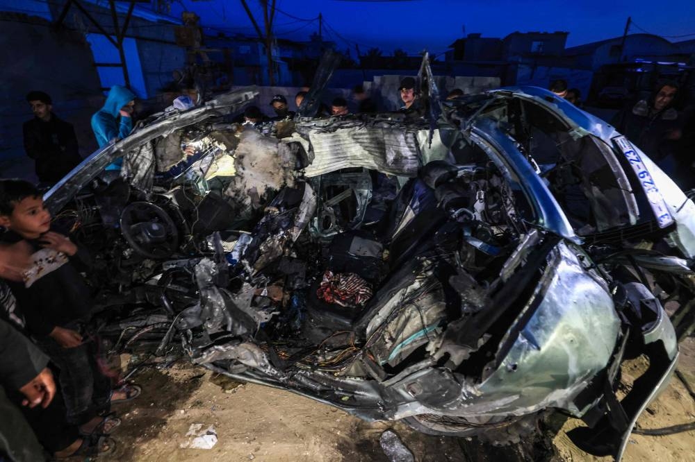 Palestinians inspect the carcass of a car reportedly hit by an Israeli strike in Rafah in the southern Gaza Strip on Saturday. AFP