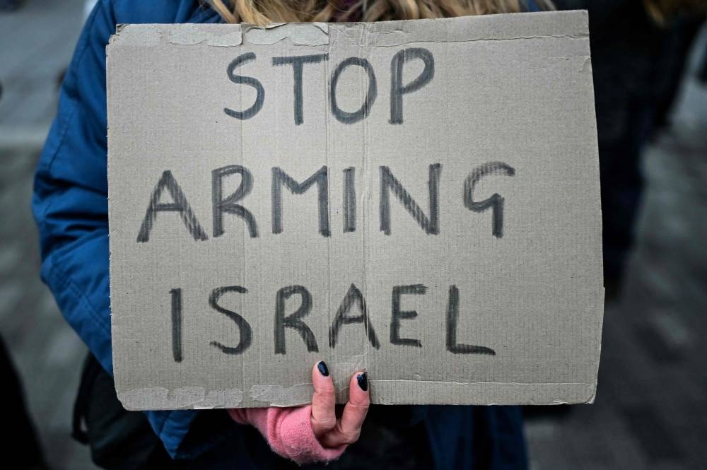 A pro-Palestinian supporter holds a placard while taking part in a "Day of Action for Palestine" demonstration outside the British multinational arms, security and aerospace company BAE Systems, in London, on Saturday. AFP