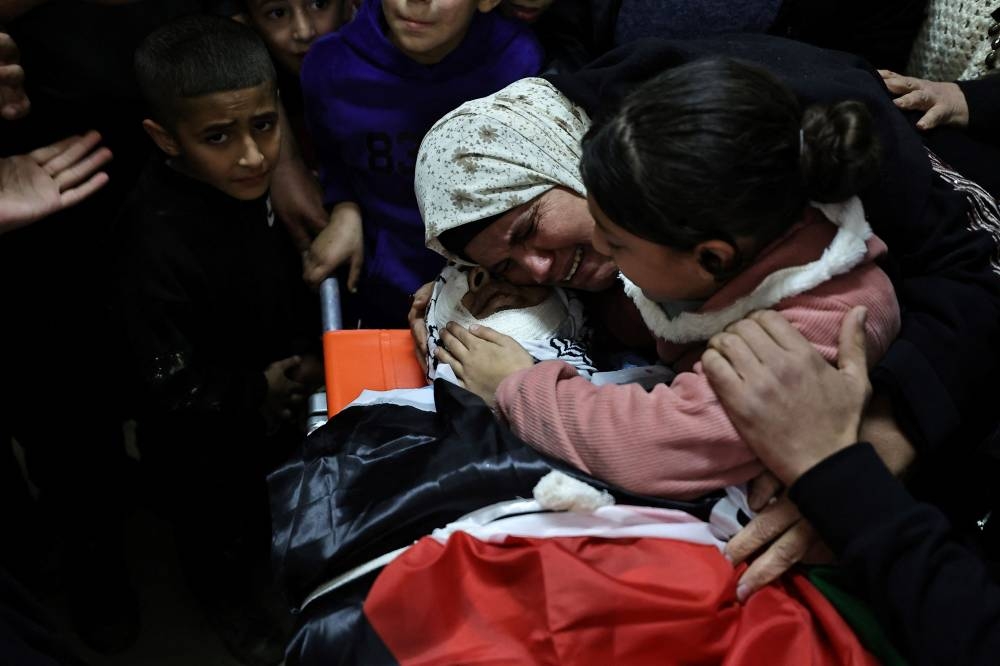 Relatives mourn over the body of one of the Palestinians, who were killed during a days-long Israeli raid, during their funeral in a refugee camp in Tulkarm in the occupied West Bank on Friday. AFP