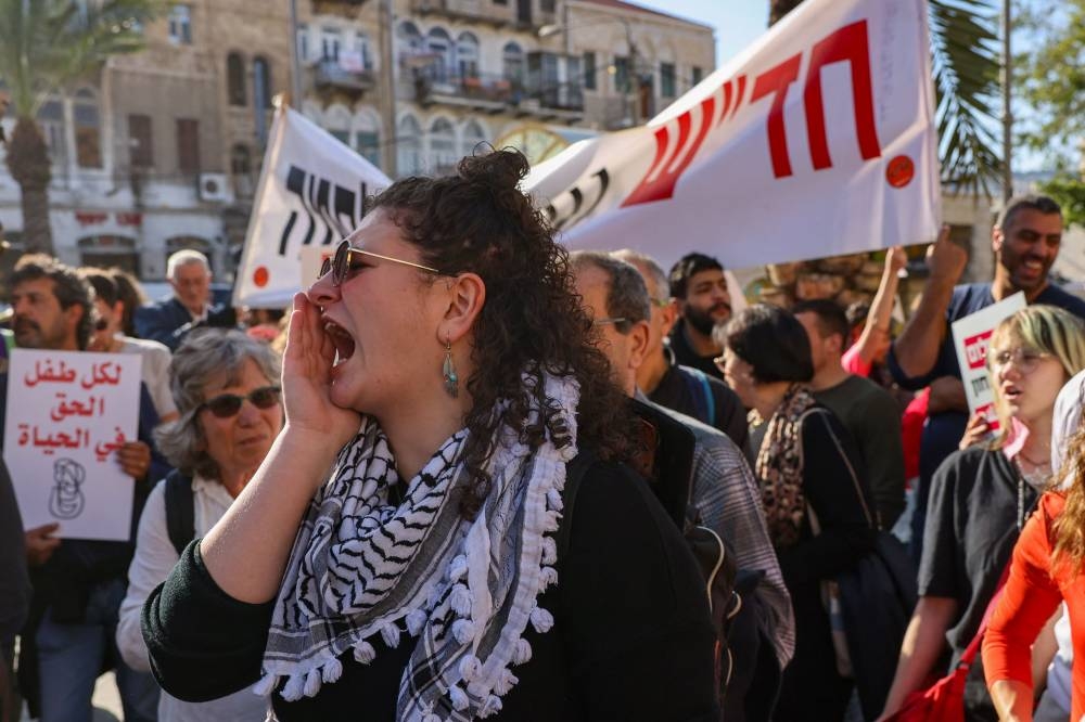 People hold placards and shout slogans as they take part in a protest calling for a ceasefire and for the release of Israeli hostages held in Gaza, in the northern port city of Haifa Saturday. AFP