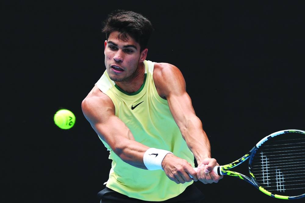 Spain’s Carlos Alcaraz hits a return against China’s Shang Juncheng during their singles match in Melbourne on Saturday. (AFP)