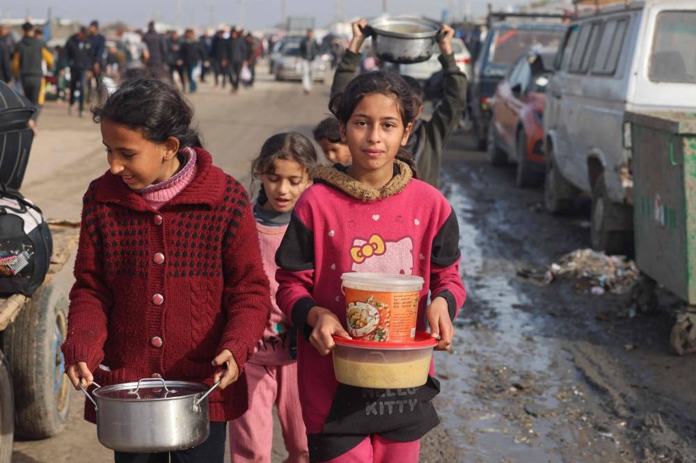 Displaced Palestinian children carry food rations they received at a makeshift tent camp in Rafah near the border with Egypt in the southern Gaza Strip, on Sunday. AFP
