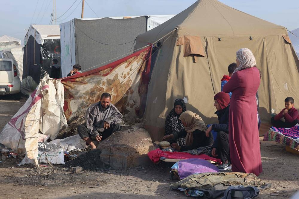 Displaced Palestinians bake bread in a traditional clay oven near their tent at a makeshift camp in Rafah near the border with Egypt in the southern Gaza Strip, on Sunday. AFP