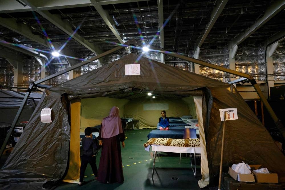 A Palestinian child sits on a bed under a tent onboard the French LHD Dixmude military ship, which serves as a hospital to treat wounded Palestinians, as it docks at the Egyptian port of Al-Arish, on Sunday. AFP
