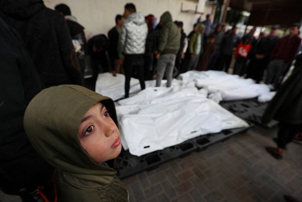 A child looks on as mourners react next to the dead bodies including four Palestinians killed in an Israeli strike on a car, in Rafah in the southern Gaza Strip, Sunday. REUTERS