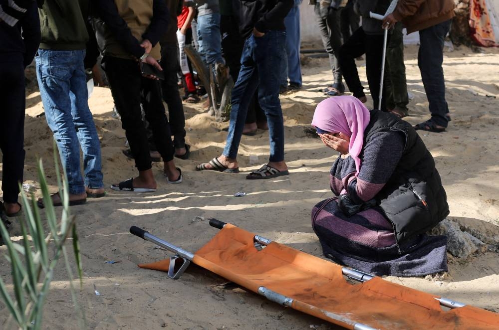 A woman reacts while people bury bodies of Palestinians killed in an Israeli strike, at the Nasser hospital premises as Palestinians cannot reach the cemetery due to the Israeli ground operation, in Khan Younis in the southern Gaza Strip, on Monday. REUTERS
