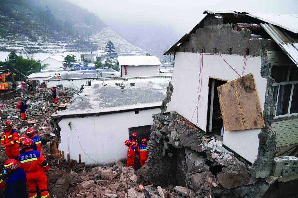 Rescue workers search for missing victims at a damaged house following a landslide in Liangshui village at Zhaotong, in southwestern China's Yunnan province. 
