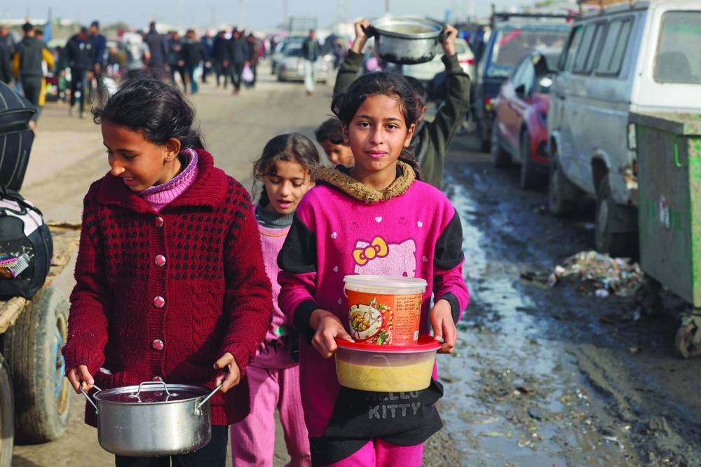 
Displaced Palestinian youths carry food rations they received at a makeshift tent camp in Rafah near the border with Egypt in the southern Gaza Strip. 