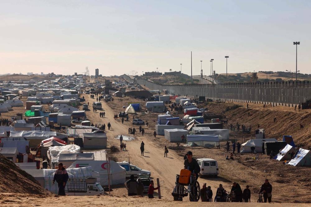 People ferry water at a makeshift tent camp for displaced Palestinians in Rafah near the border with Egypt in the southern Gaza Strip, on Wednesday. AFP