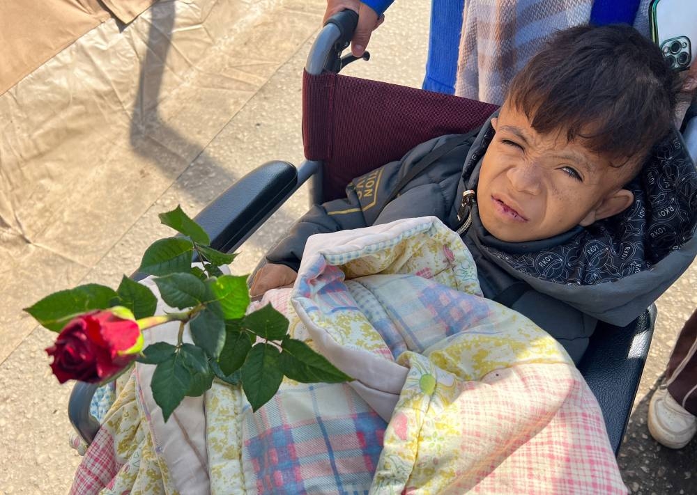 Palestinian teenager Rafat Al-Satari, a kidney patient whose mother and two of his siblings were killed in an Israeli strike, holds a red flower handed out to him by florist Hussam Abdulhadi, in Rafah in the southern Gaza Strip, on Wednesday. REUTERS
