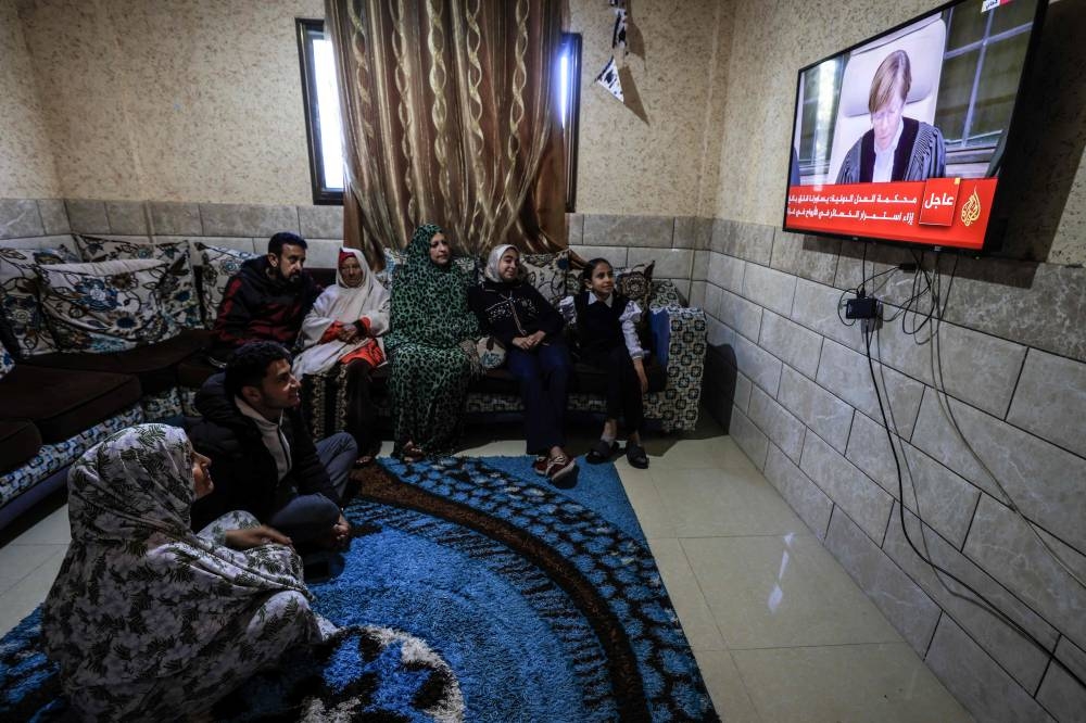 Members of a Palestinian family watch on a television set, the UN's top court in the Hague reading its initial decision in a case accusing Israel of genocide, in Rafah in the southern Gaza Strip on  Friday. AFP