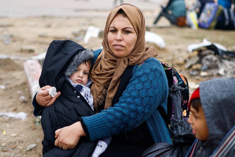 A woman holds a child as Palestinians fleeing Khan Younis, due to the Israeli ground operation, move towards Rafah in the southern Gaza Strip, on Saturday. REUTERS
