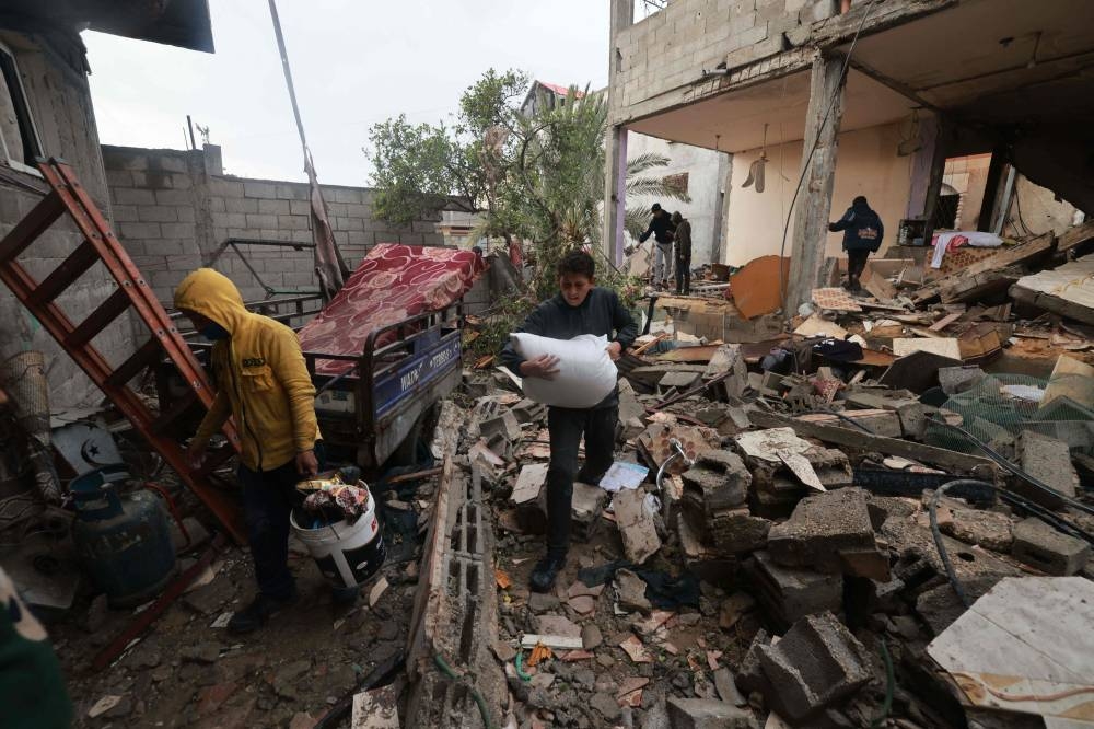 People salvage objects amid the rubble of a building destroyed by Israeli bombing in Rafah in the southern Gaza Strip on Saturday. AFP