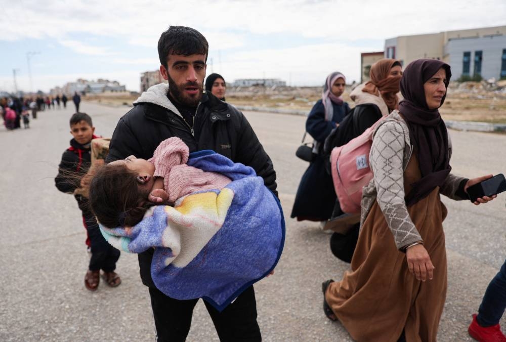 A man carries an injured child as Palestinians fleeing Khan Younis, due to the Israeli ground operation in the southern Gaza Strip, on Sunday. REUTERS