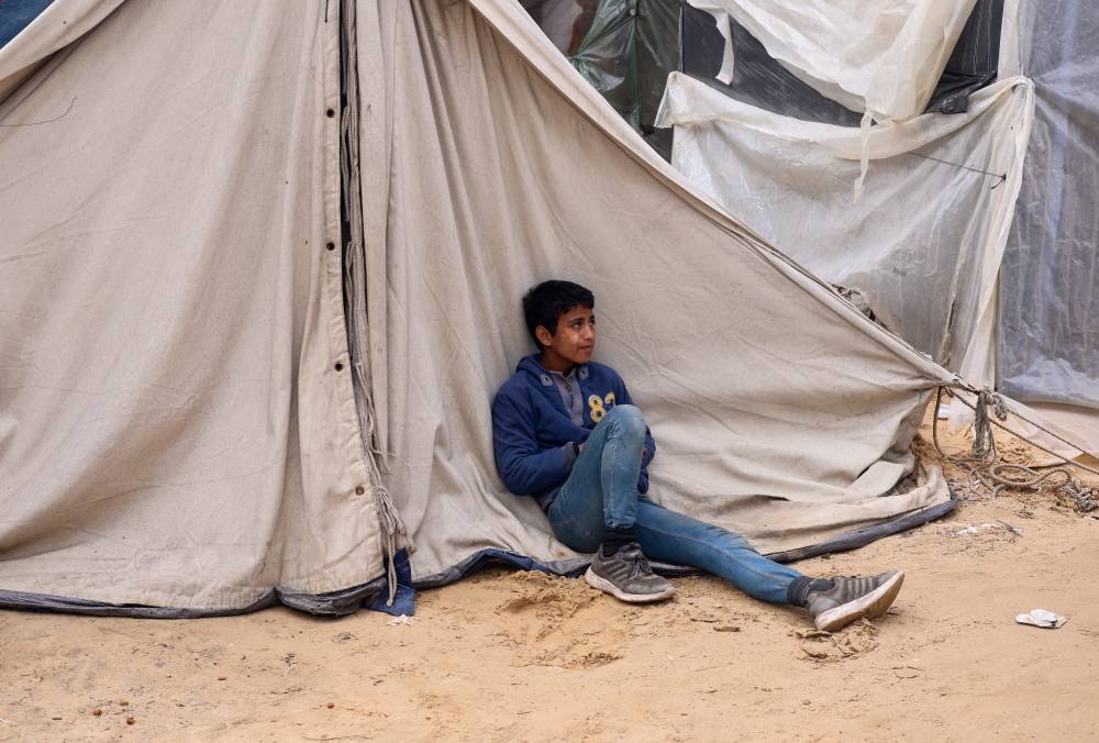 A boy sits outside a tent as displaced Palestinians, who fled their houses due to Israeli strikes, shelter at a tent camp in Rafah in the southern Gaza Strip, on Sunday. REUTERS